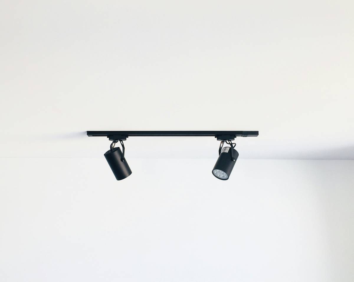 Modern track lighting home office setup with adjustable black track heads illuminating a wooden desk and monitor